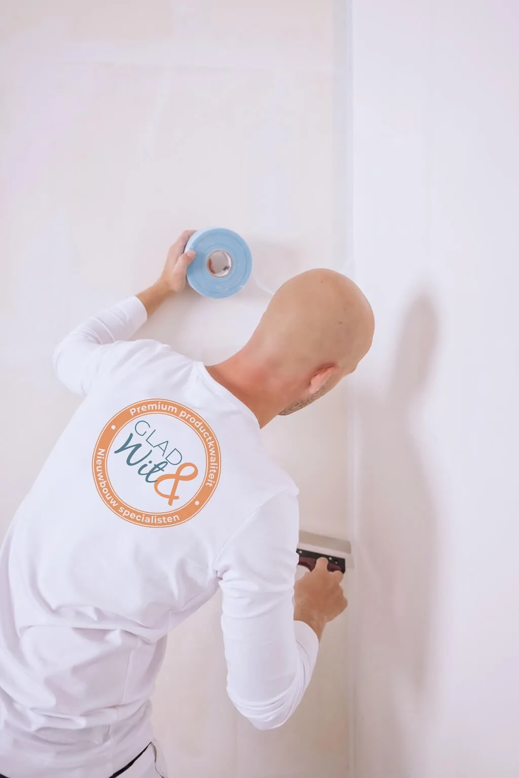 Stukadoor van Glad&Wit brengt afplaktape aan op een wand